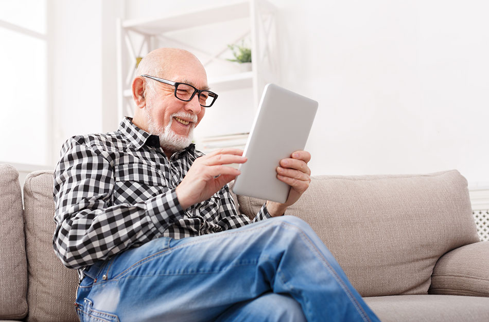 senior man wearing reading glasses holding tablet