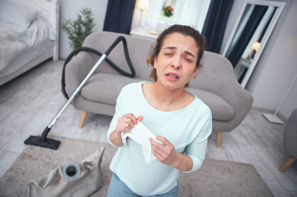 allergic woman holding tissue, open vacuum in living room