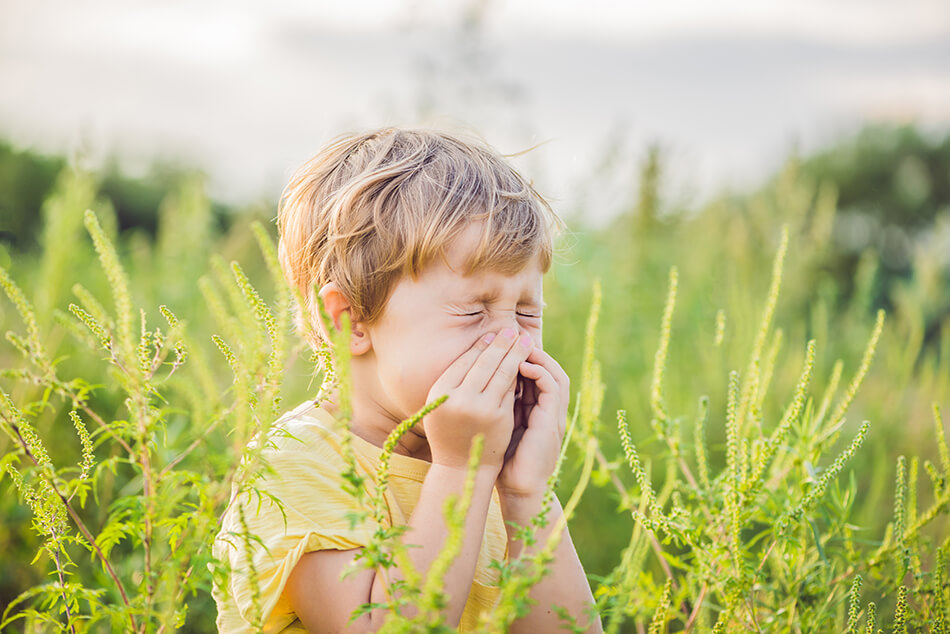 boy is outdoors bothered by seasonal allergies