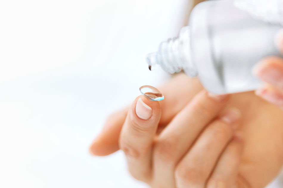 cleaning contact lens with bottle of solution