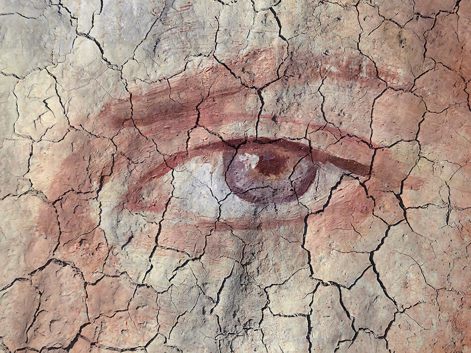 dry cracked earth superimposed over close-up of a human eye