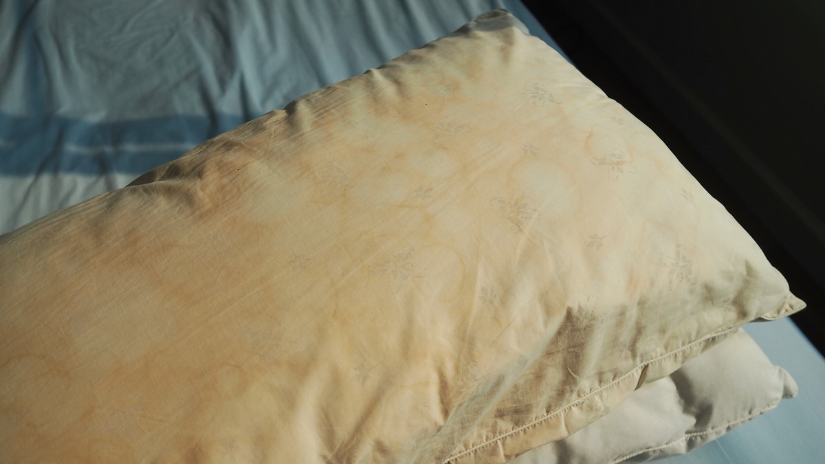 Dirty pillows stacked on bed