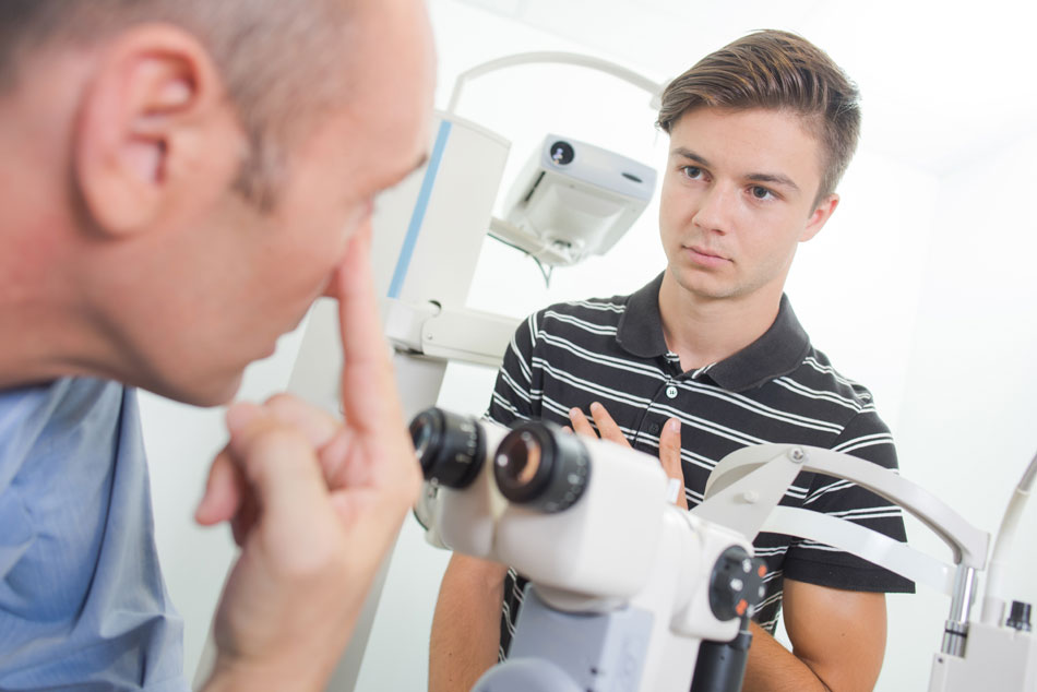 Eye doctor instructing young male patient during contact lens fitting