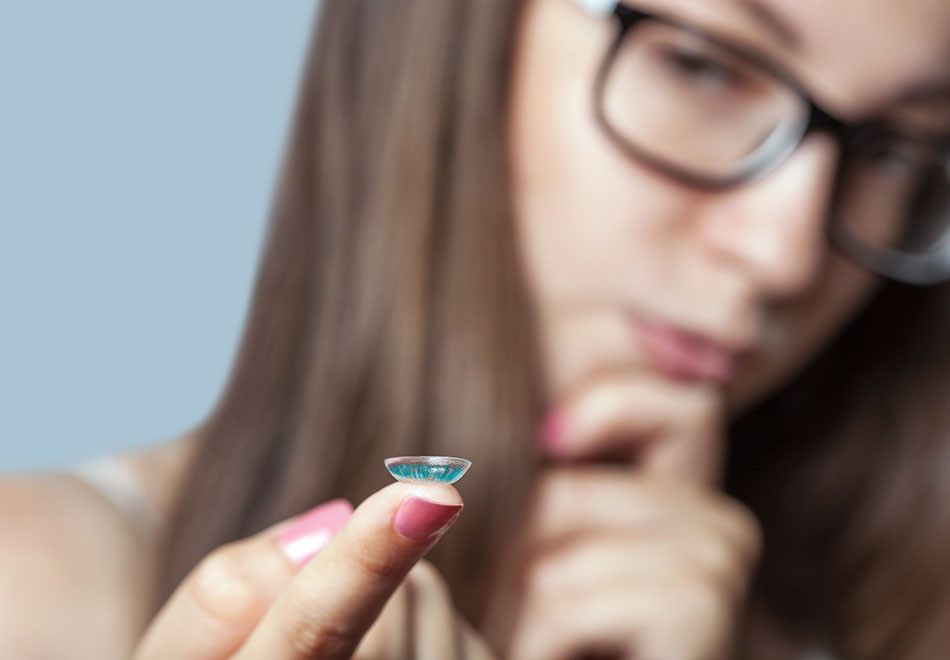 girl with colored contact lens on finger thinking about sharing contact lenses