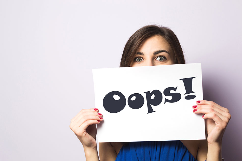 Girl holding an Oops sign in front of her face