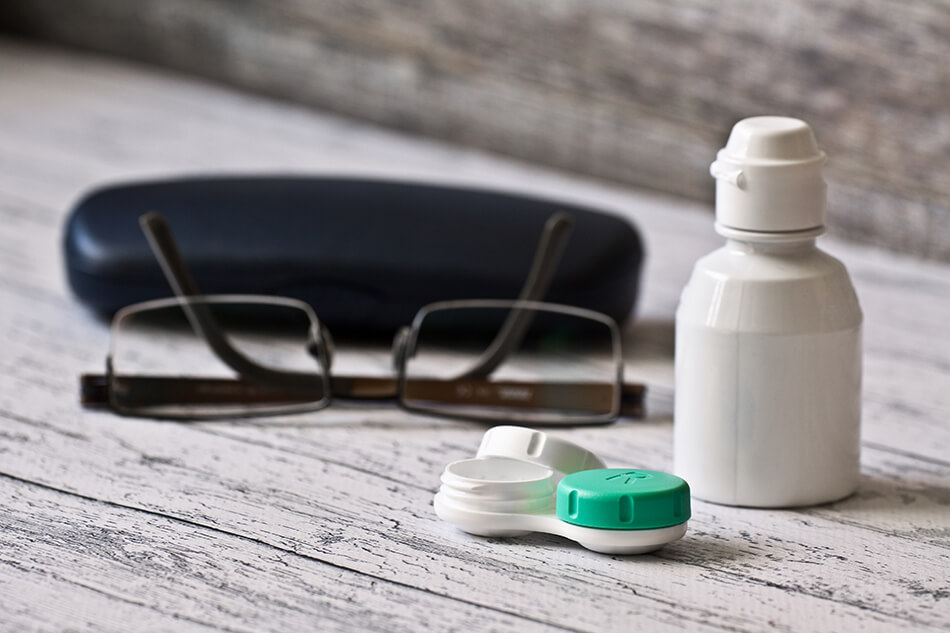 glasses, glass case, contact lens care and contact solution on a table
