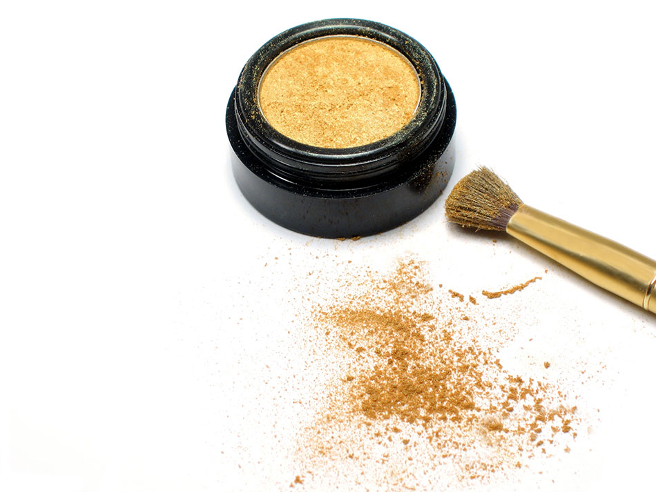 gold eyeshadow and brush on white background