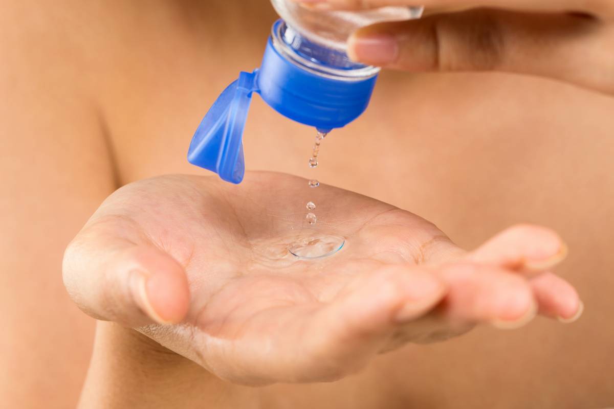 close-up of hands cleaning contact lens with solution bottle