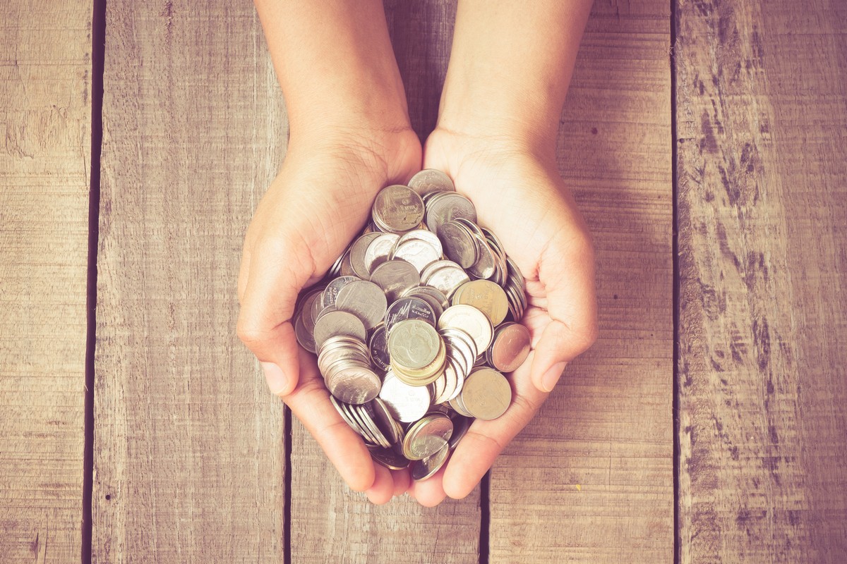 hands holding coins on wood table