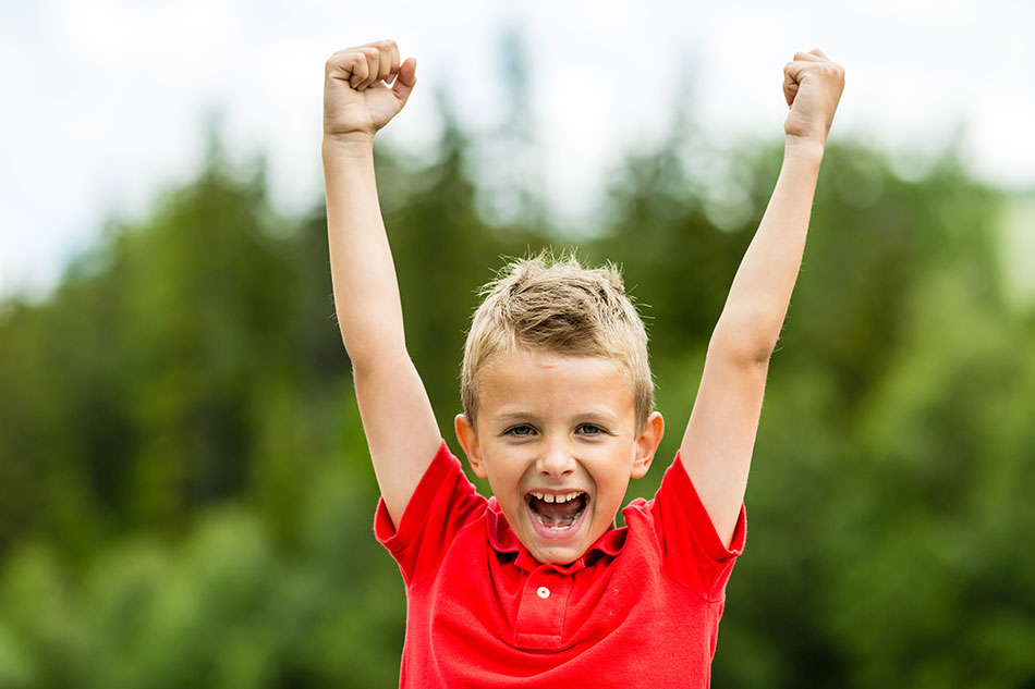 Happy confident boy with raised arms