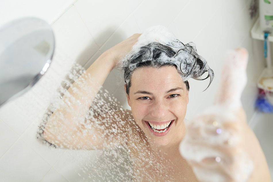happy woman taking shower with shampoo in hair