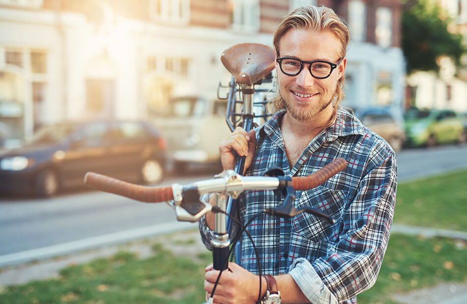man wearing glasses and carrying his bike on his shoulder