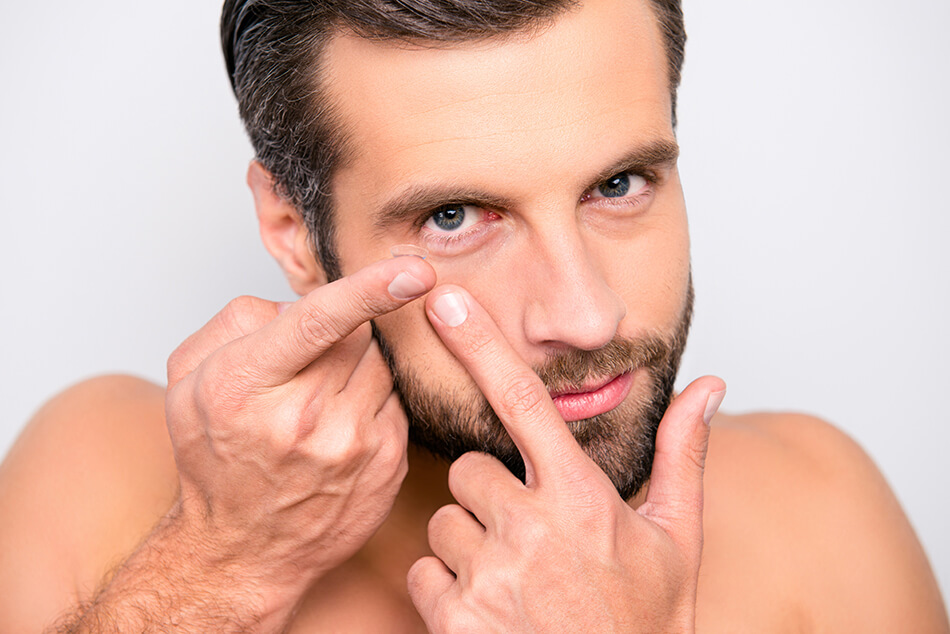 man putting contacts in right eye