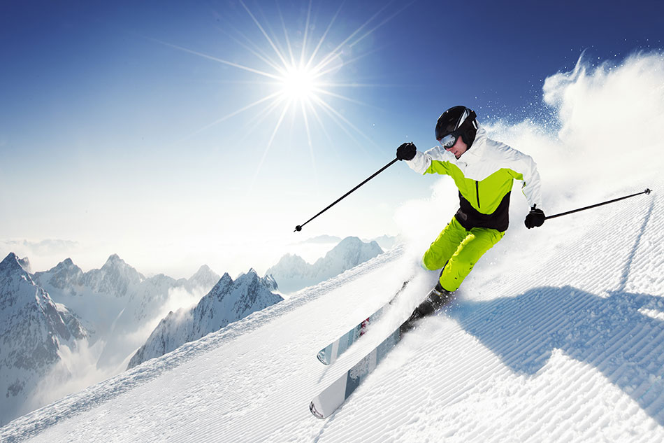 man in white and yellow ski suit coming down mountain in the sunshine