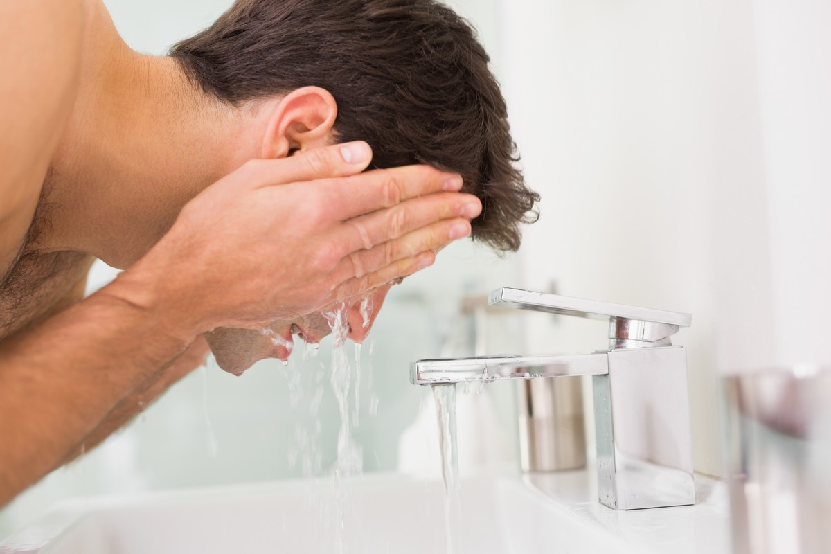 Man washing face in bathroom sink