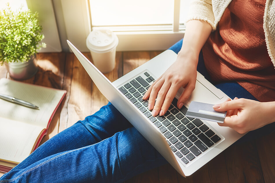 person sitting on floor shopping online with credit card in hand