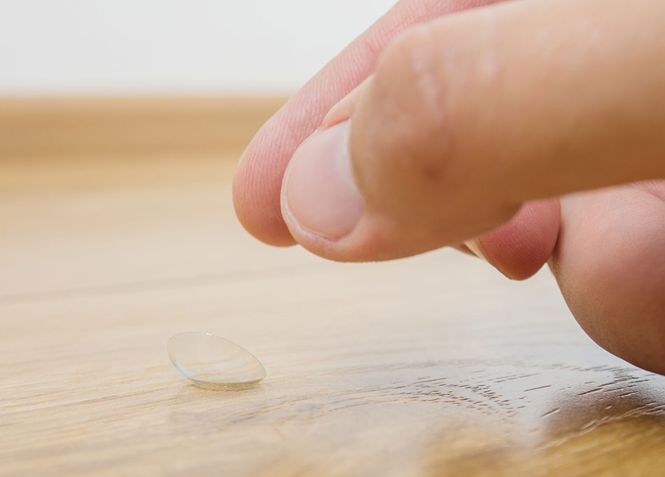 Picking up a contact lens from a wooden floor