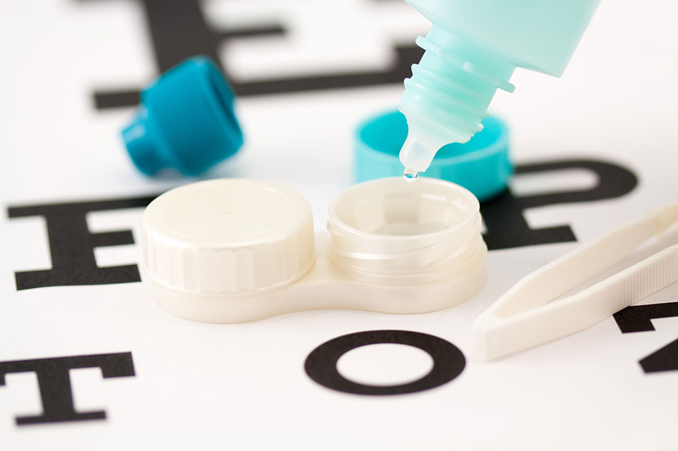 pouring blue contact solution bottle into open contact case