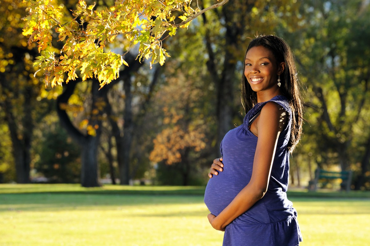 a pregnant woman standing outside smiling