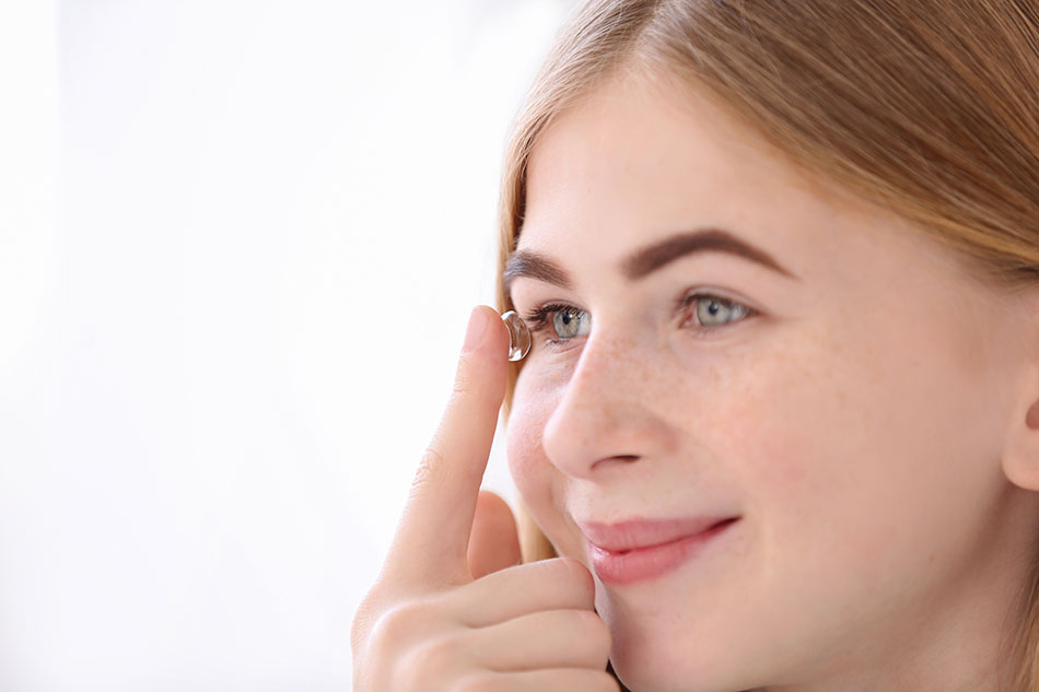 Smiling teen girl putting in contact lens