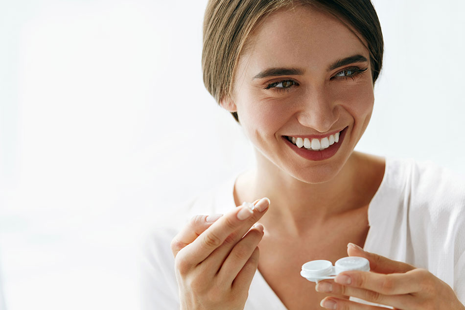 smiling woman holding contact case and contacts