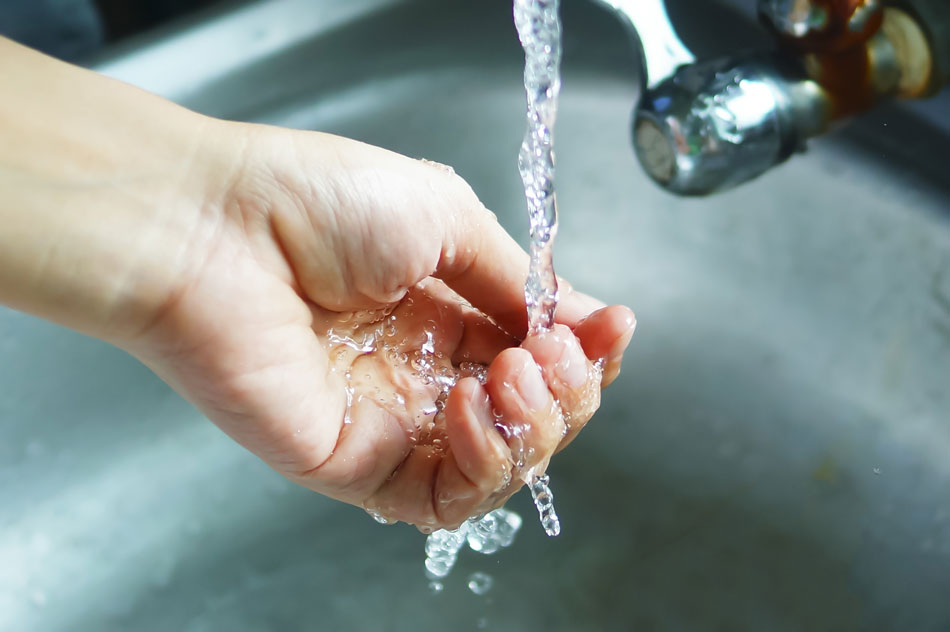 water flowing from tap into person’s hand