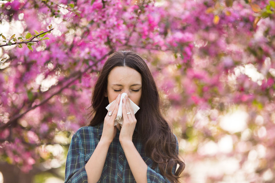 Woman with allergies and contacts blowing nose