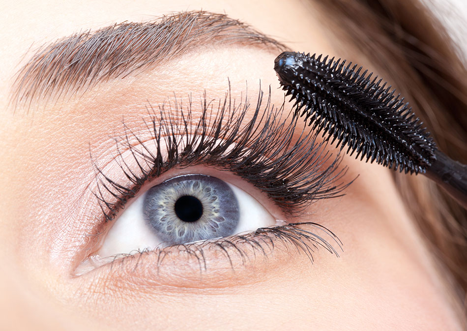 woman with blue eye putting on mascara