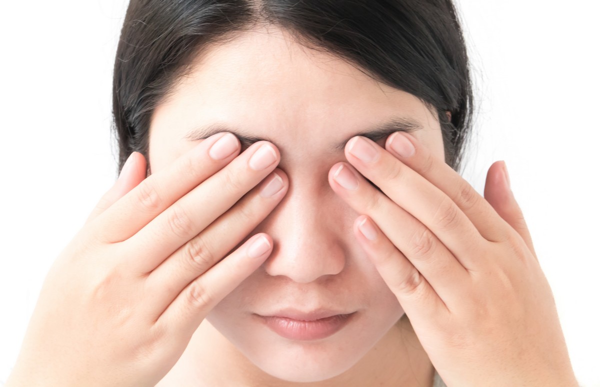 Woman covering both eyes with hands