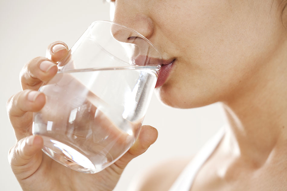 woman drinking water from clear glass