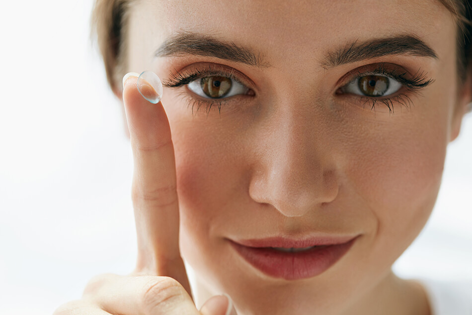 woman holding up index finger with contact lens