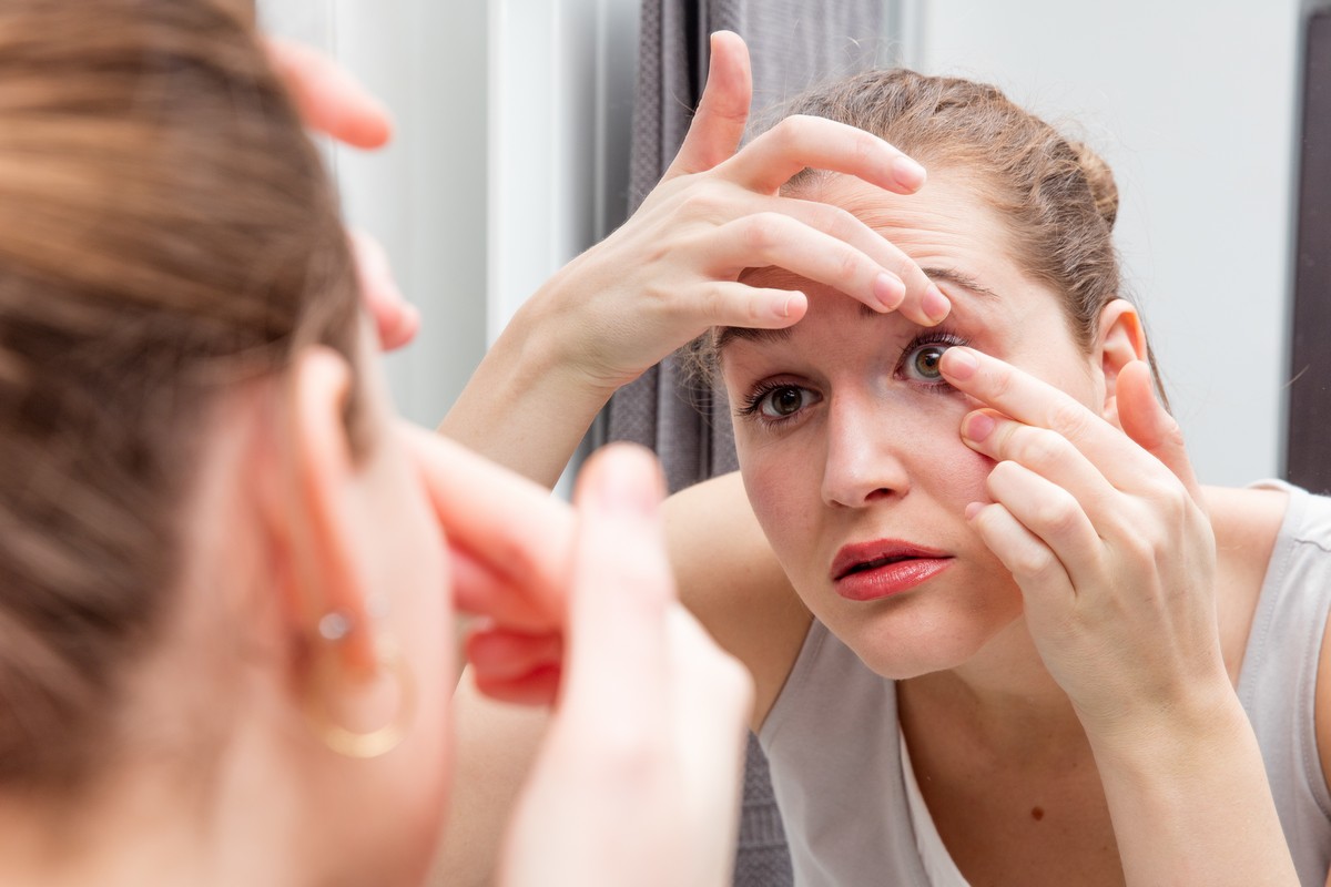 hwoman inserting contact lens in right eye