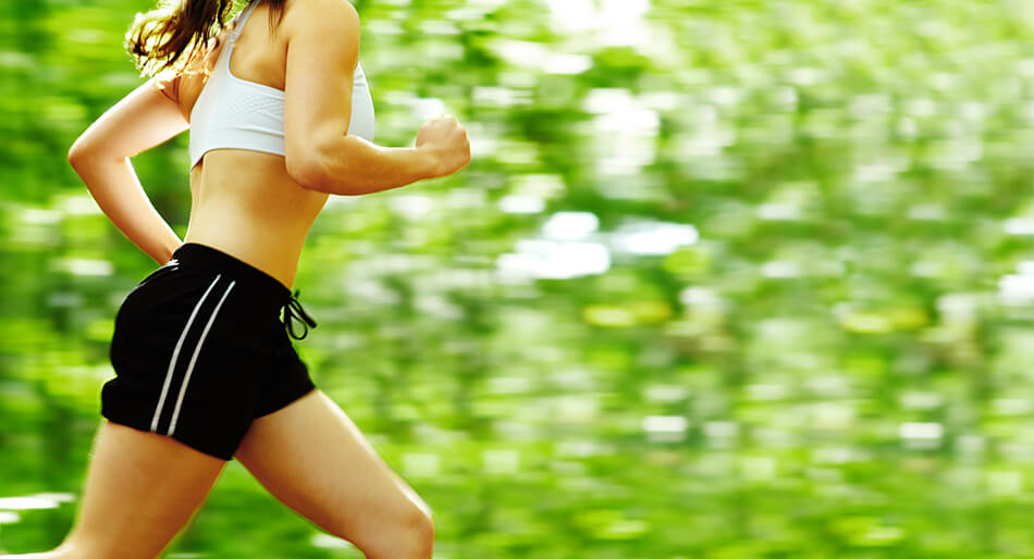 woman jogging next to green trees