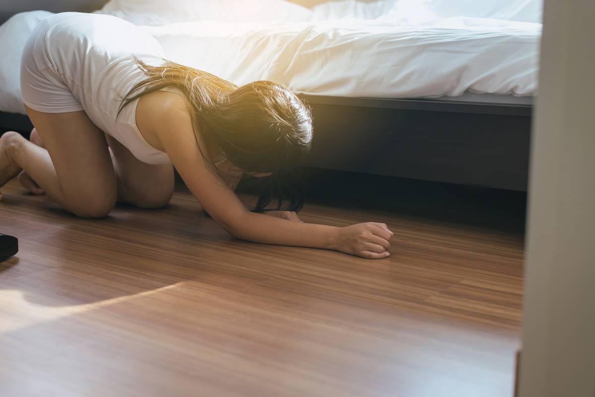 woman trying to find a contact lens under bed