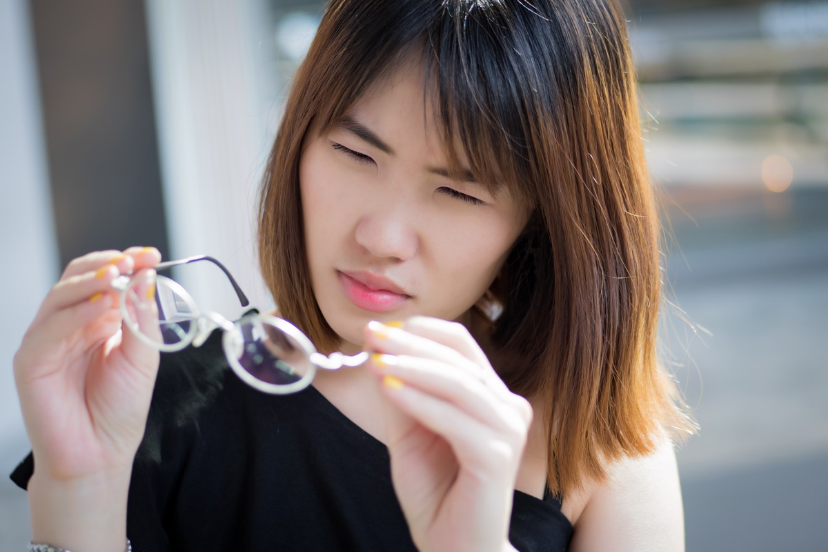 woman with poor vision holding glasses pondering contact lenses