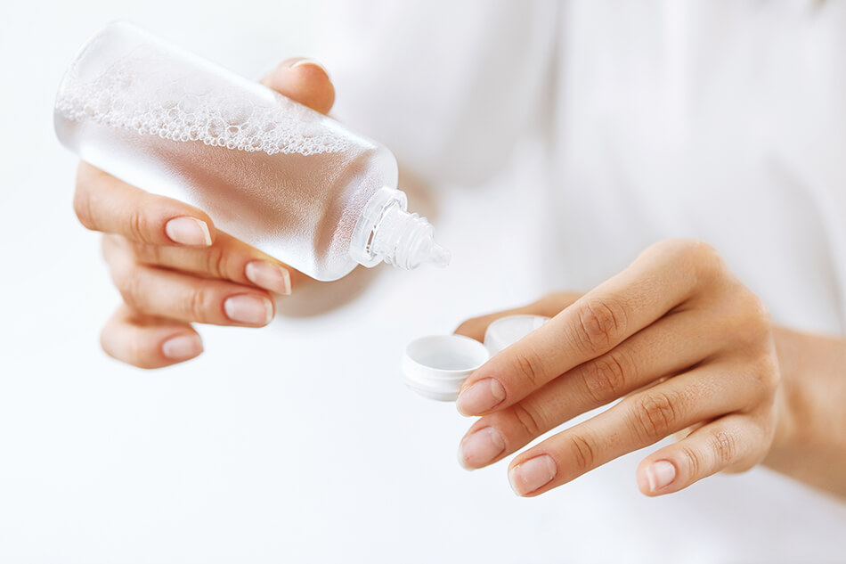 woman pouring contact lens solution into contact case