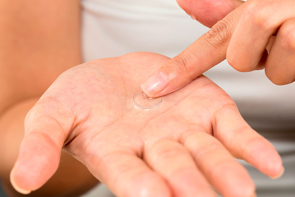 Woman rubbing contact lens in her palm with her finger
