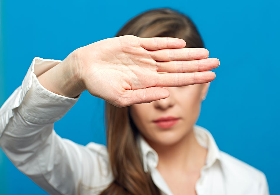 woman showing stop symbol with outstretched hand covering her eyes