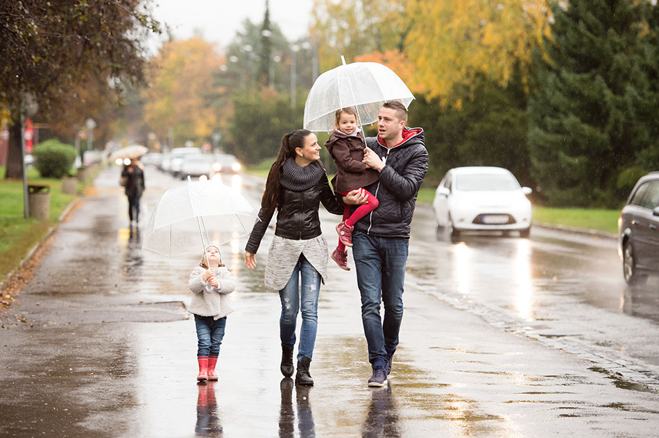 Young family of four enjoying a walk on a rainy day