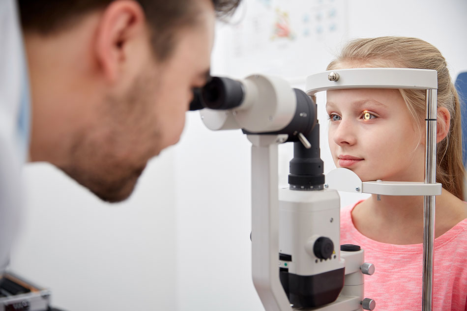 Young girl getting eye scanned by male optometrist