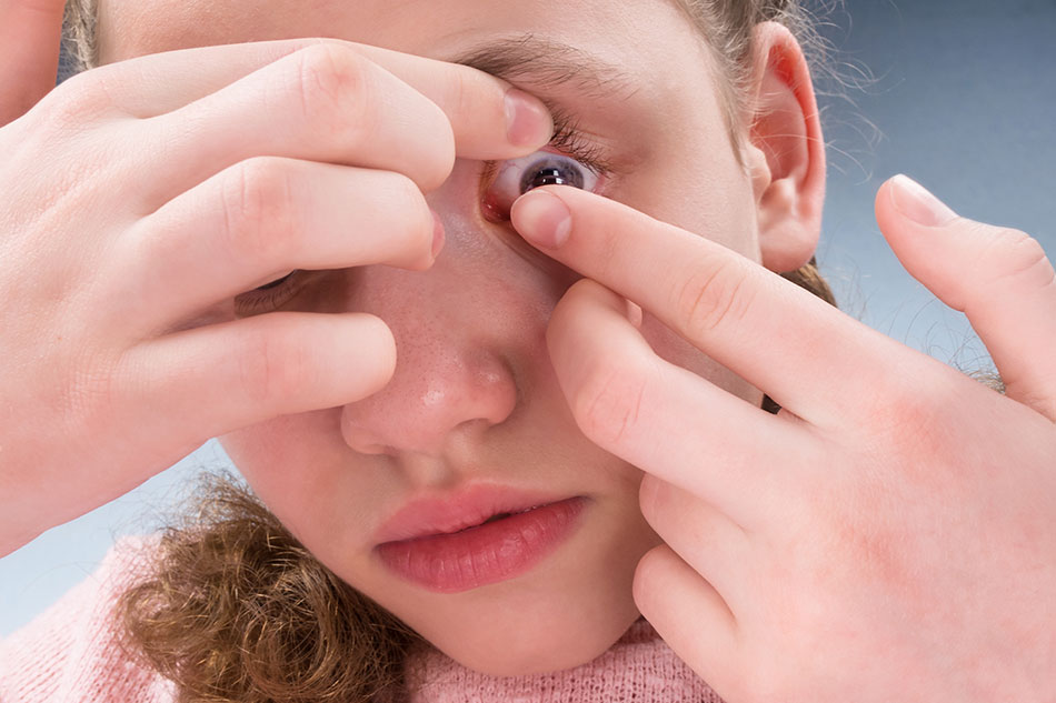 young girl inserting contact lens
