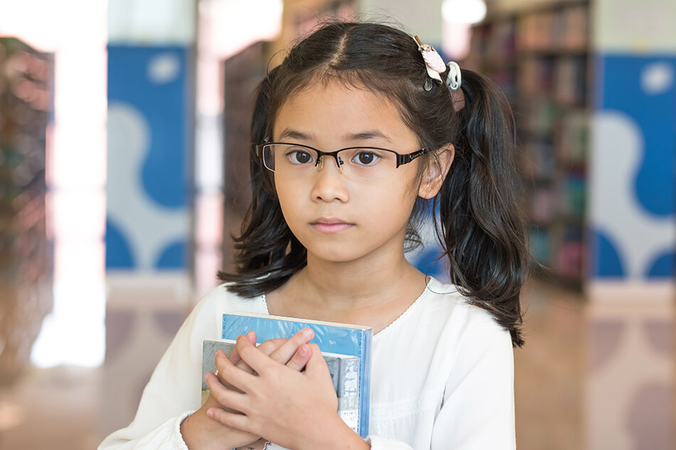 young girl wearing glasses holding books