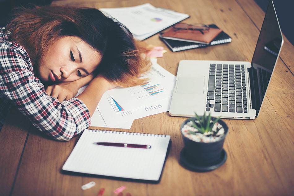 young woman taking nap on desk after taking contact lens care quiz